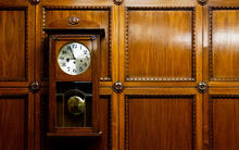 wood pendulum clock hung on a wood paneled wall