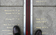 pair of feet standing on either side of the prime meridian in Greenwich, England