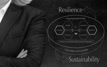 Female business leader standing with arms crossed on dark background beside the Baldrige Overview with arrows pointing to Resilience and Sustainability.