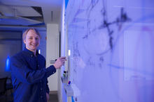 Alexey Gorshkov poses at a whiteboard, holding a marker. 