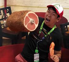 Leon Chao poses pretending to bite into a huge piece of fake meat. 