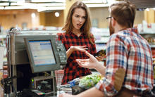 Photo of angry woman checking out at the supermarket speaking to the cashier.