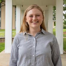 Christine McGinn poses smiling for a head shot outdoors on the NIST Gaithersburg campus. 