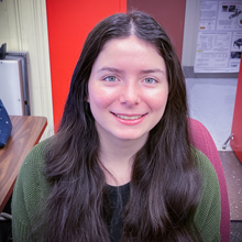 Isabelle Rivera poses for a head shot at her desk. 