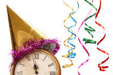 An antique clock showing a few minutes before 12 is topped with a party hat, and colorful streamers hang in the background. 