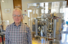 Antonio Possolo stands next to a museum display of a Kibble balance, a complex scientific device.