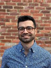 Brian Gutierrez poses outdoors in front of a brick wall. 