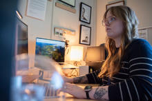Sierra Miller sits at a desk facing a computer screen.