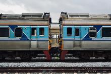 A detailed view of two connected blue and silver train cars on a railway track.