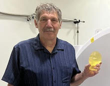Stephen Russek poses in the lab holding a small model of a human head.