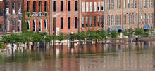 Floodwaters rise to the doorways of a row of historic brick buildings, one with a sign saying "Nashville."