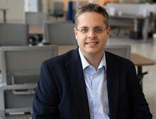 Andrew Regenscheid poses sitting at a table in the NIST library. 