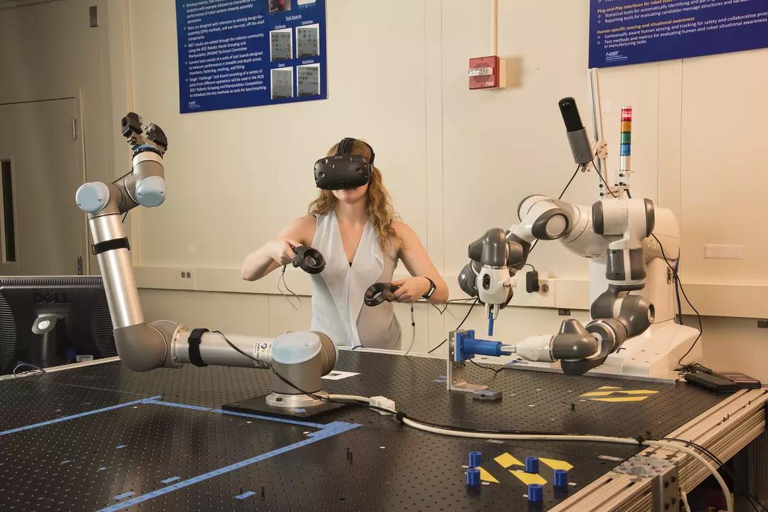 Researcher Megan Zimmerman wearing a virtual reality headset and handheld devices to control 2-handed tasks of a robot