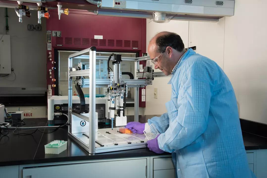 Researcher John Elliott in the lab loading samples into automated liquid handling instrument.