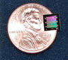 NIST's superconducting circuit containing a 'micro drum' sitting atop of a penny to show how much smaller it is.