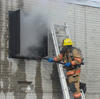 During a fire safety experiment, a firefighter ventilates the building to let smoke and heat out to improve conditions inside.