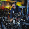 David Wineland leans over a table of lasers to adjust a laser beam