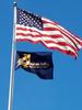 Baldrige program flag and American flag waving on steel pole against blue sky