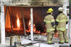 Two firefighters look over the last flames inside a compartment where the flammability of cross-laminated timber buildings is being tested.