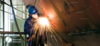 man welding the side of a boat