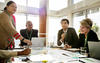 A group of diverse women and men sitting at a table discussing a topic.