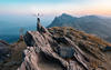 A man standing on top of a mountain with his arms out.