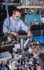 Man in glasses stands behind a table with a number of wires and lattices.