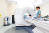 a CT scanner with technician and patient