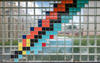 a glass brick wall with blue, orange, yell, black, turquoise, and red bricks in a pattern representing different isotopes