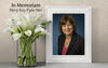 In Memoriam: Photo of Mary Kay Fyda-Mar with white lilies in a vase beside frame.