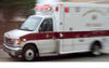 white ambulance with red trim and letters on side with lights flashing as it responds to a call