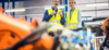 people looking at robots in action in a manufacturing facility