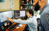 Tytus Mak sitting at his desk and while colleague Arun Moorthy and he look at a computer screen