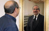 Photo of Harry Hertz looking at a reflection in the mirror of his doppelgänger in a tuxedo.