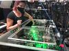woman makes adjustments to optics on a laser bench