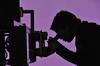 A shadow image with purple background of a male scientist looking at a microscope