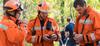 Group of uniformed first responders in a forest holding two-way radios