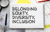 Notebook on desk with the words belonging, equity, diversity, and inclusion.