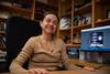 Ana Maria Rey sits at desk in an office and smiles for a photo.