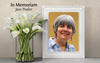 In Memoriam: Photo of Jane Poulter with white lilies in a vase beside frame.