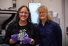 Diana Ortiz-Montalvo, wearing safety glasses and holding a small circular filter with tweezers, poses with Abigail Lindstrom in the lab.