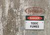 Photograph of a weathered metal surface labeled Danger Toxic Fumes