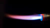 Photograph of a long pink flame against a black background, emanating from a torch, with small blue cone near the base of the nozzle.
