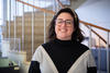 Kathryn Miller poses smiling in front of a spiral staircase in the NIST library. 