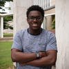 Miles Walker poses smiling, with his arms crossed, outside a building on the NIST campus. 