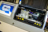 A photo of a rapid DNA typing instrument.  A screen controls the interface and a chip is loaded into the instrument. 