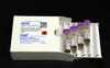 A white box labeled "8048 Human Fecal Material" lies open, with a tray of four plastic vials pulled out. 