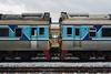 A detailed view of two connected blue and silver train cars on a railway track.