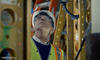 Photo of structural elements surrounding man with helmet and glasses looking up 