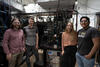 Four researchers pose standing around a large piece of scientific equipment covered with wiring and electronics. 
